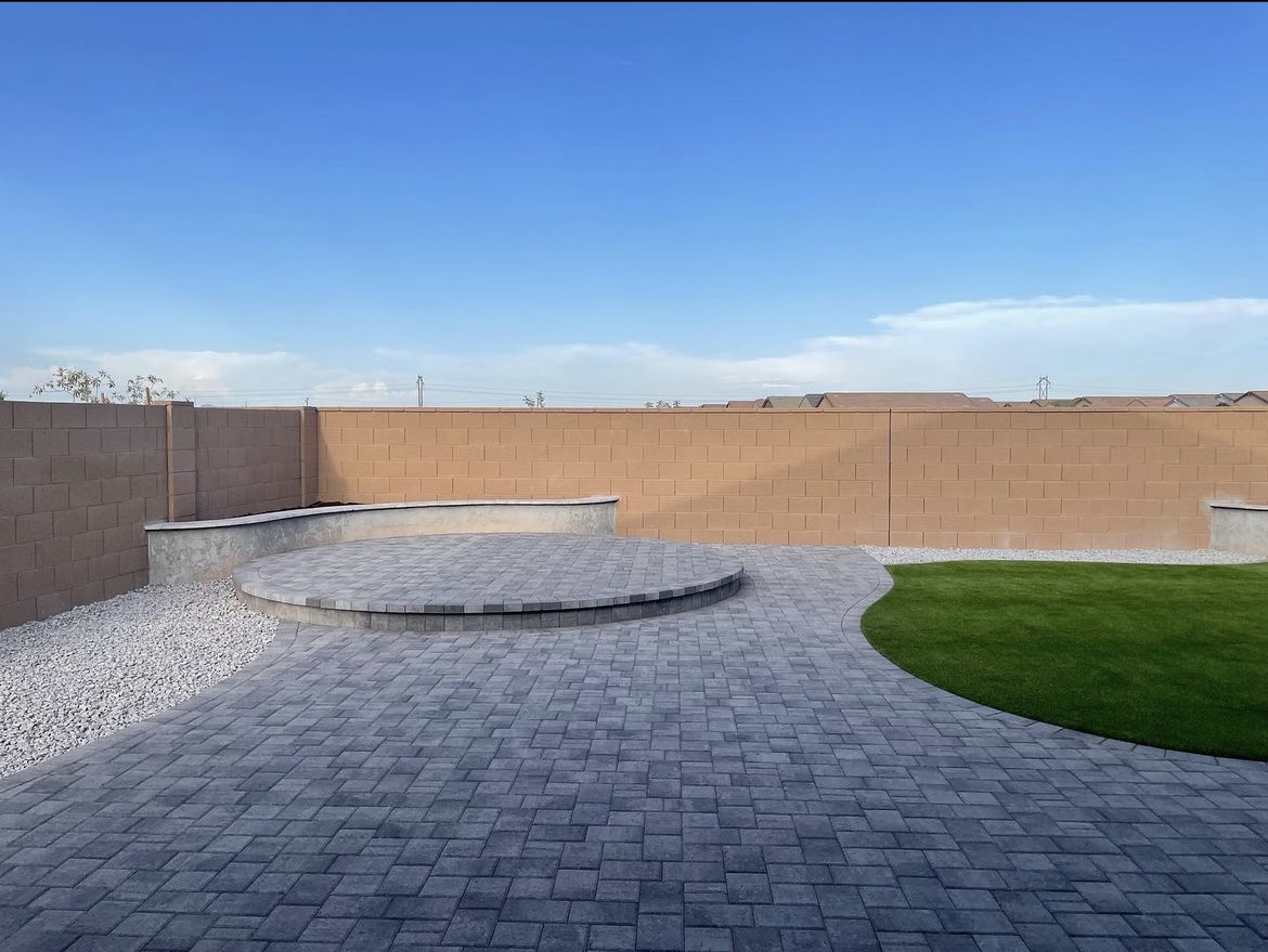 Circular raised paver seating area with a curved turf border